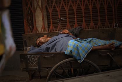 A man taking a nap in the streets of Delhi. With working hours up to 18 hours a day, a nap is well needed. Read about the sleeping man on this hand-pulled cart and the working conditions in India in this archive story.